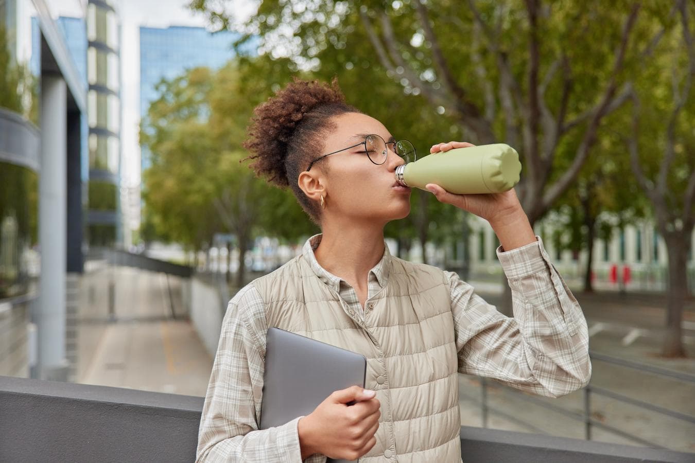a girl drinking out of a reusable water bottle eco friendly office supplies company culture unique company swag remote employees promotional products