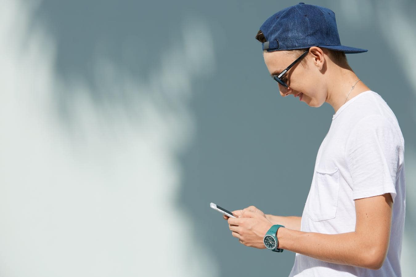 a man looking at his phone wearing a blue hat custom swag boxes swag bag tech accessories coffee swag bag custom swag boxes company swag ideas fitness gear