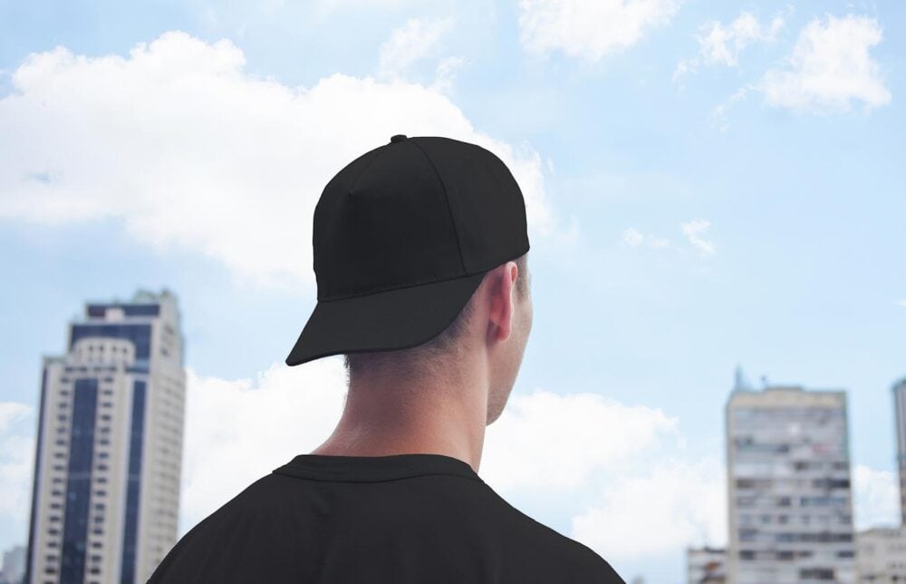 a man wearing a baseball cap looking over a city bill new era cap tips brim create style bend worry wet heat moisture style pull brim curve hats