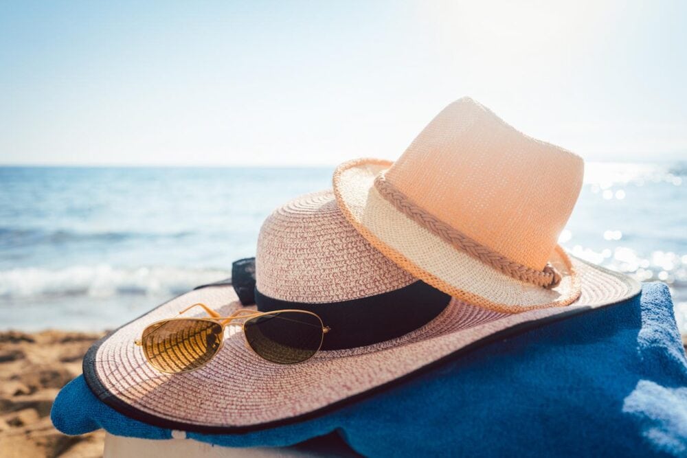 beach hat and sunglasses by the ocean in the sand