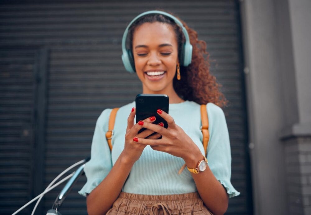 woman with headphones on her phone eventually create make merch designer merch strategy own store all the tools built in marketing tools t shirt templates